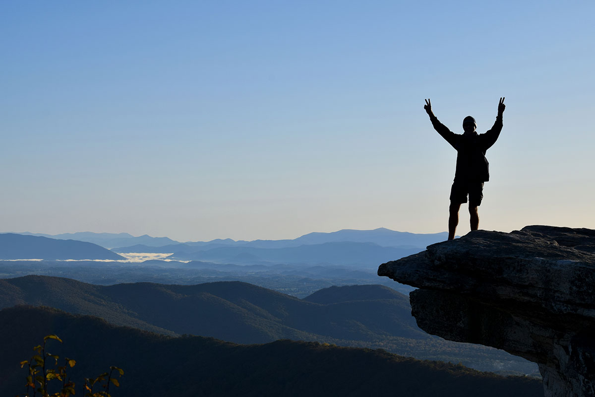 Silhouette of a man standing on McAfee Knob ledge at sunrise on the Appalachian Trail in Virginia.
